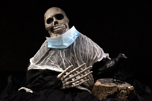 A human skeleton is wearing a protective surgical face mask for Halloween.