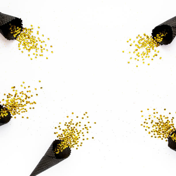 istock Black waffle cones with golden confetti tinsel isolated on white background. Flat lay, top view minimal festive concept 1271216084