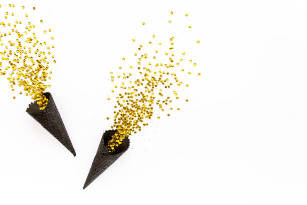 istock Black waffle cones with golden confetti tinsel isolated on white background. Flat lay, top view minimal festive concept 1271217781