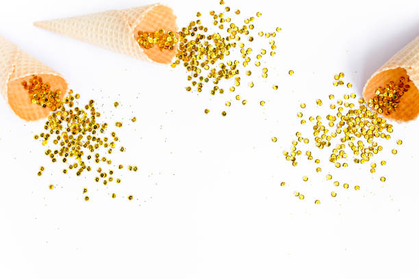 istock Yellow waffle cones with golden confetti tinsel isolated on white background. Flat lay, top view minimal festive. Holiday and celebration concept 1271217880