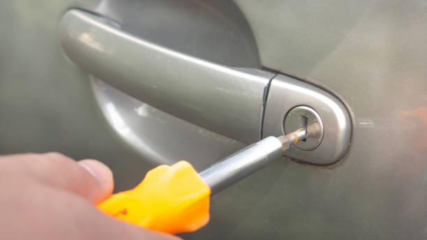 a man opens a gray car with a screwdriver to steal stock photo