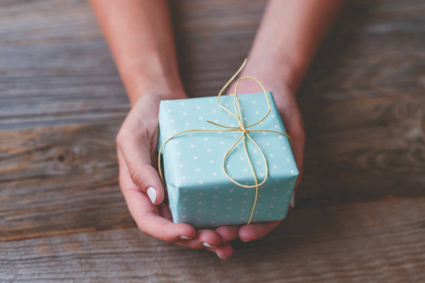 mujer sosteniendo una caja de regalo con un lazo de cuerda en la parte superior. - wrapped package string box fotografías e imágenes de stock