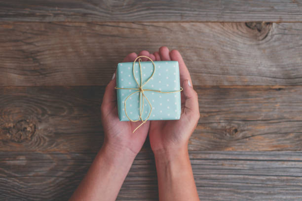 istock Woman holding a gift box with a bow of string on top. 1271220509
