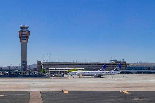 Two United Airlines Boeing 737-900ER aircrafts parked in front of a parking structure at Phoenix Sky Harbor International Airports in April 2020. On the left is the air traffic control tower.