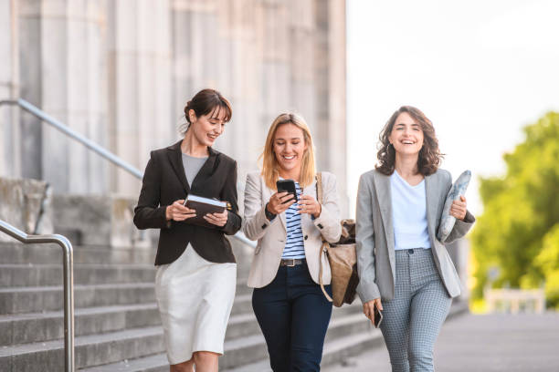 istock Smiling Female Students Walking and Checking Smart Phone 1271229404