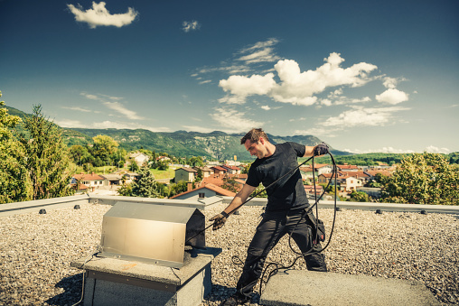 Chimney sweeper cleaning a chimney on top of the roof