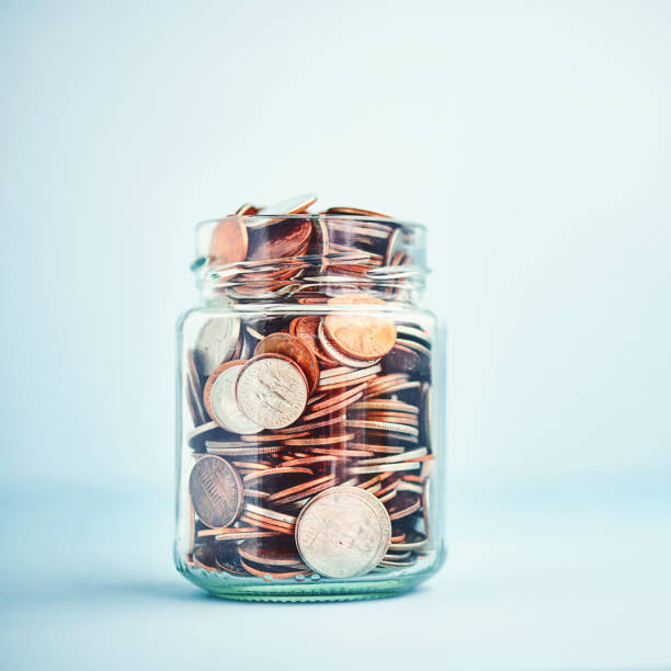 istock Change Jar Filled with Coins on Bright Blue Background 1271242602