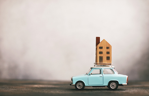 Little blue car with house on roof rack. Relocation concept