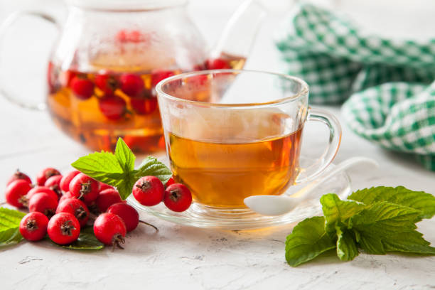 tea with a hawthorn and mint in a cup on a table, selective focus tea with a hawthorn and mint in a cup on a table, selective focus hawthorn stock pictures, royalty-free photos & images