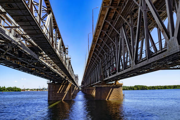 View of the Dnieper river under the Amur bridge in Dnipro (Ukraine) View of the Dnieper river under the Amur bridge in Dnipro (Ukraine). Engineering-architecture geometric background with straight lines and perspective. Water surface with copy space dnipropetrovsk stock pictures, royalty-free photos & images