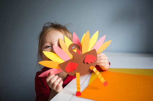 paper craft for kids. DIY Turkey made for thanksgiving day. create art for children. girl playing with a toy.
