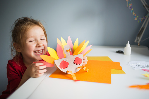 paper craft for kids. DIY Turkey made for thanksgiving day. create art for children. girl playing with a toy