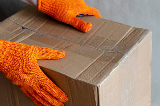 istock Hands in protective gloves hold the carton box. 1271260931