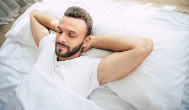 istock Handsome young bearded man is sleeping in a white big bed in a comfortable bedroom 1271264084
