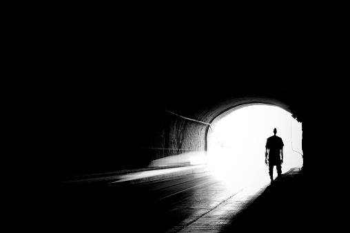 Moving silhouette of a young man in a dark tunnel in blur.