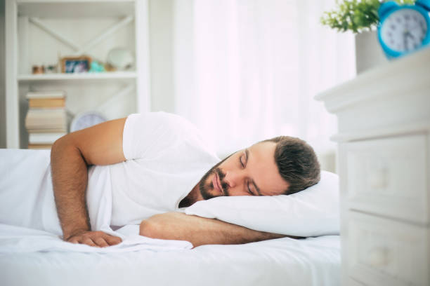 istock Handsome young bearded man is sleeping in a white big bed in a comfortable bedroom 1271265443