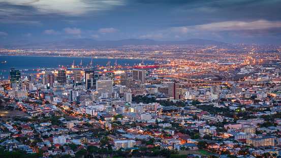 Illuminated Cityscape of Cape Town Panorama. Scenic view over Victoria and Alfred Waterfront, Century City and Woodstock Districts of Downtown Cape Town towards Cape Town Waterfront and Harbor during sunset twilight. Cape Town, South Africa, Africa