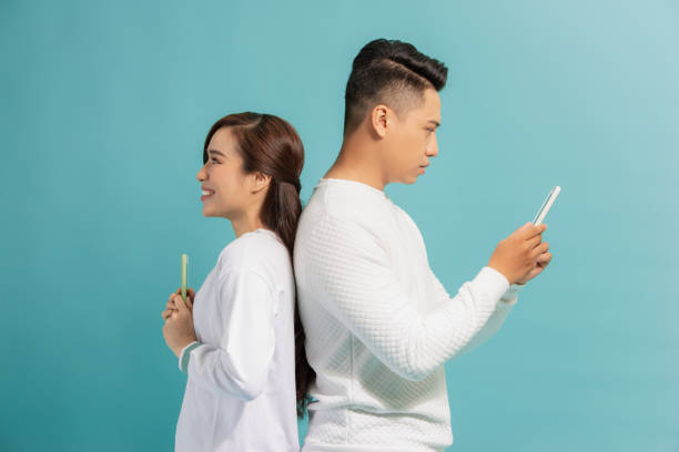 istock Distrust Concept. Beautiful young modern couple with smartphones in hands standing back to back. 1271267919