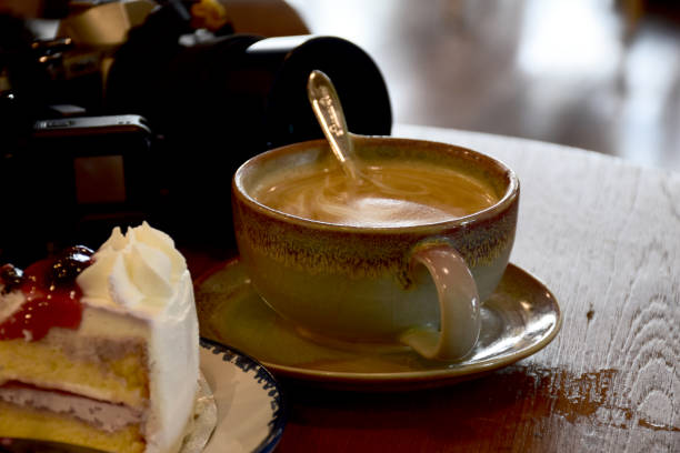 A cup of black coffee and a plate with a piece of Belgian cream cheesecake on a black background. Top view, flat lay.