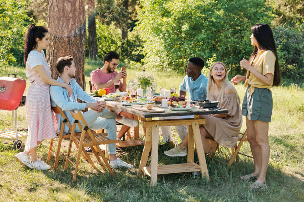 istock Young intercultural relaxed friends chatting by table after outdoor dinner 1271270803
