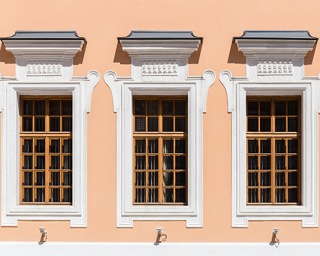 A fragment of the building's facade with three classic Windows with wooden frames.