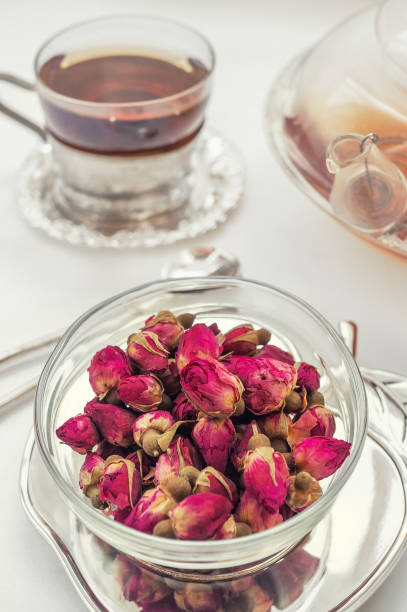 чай из розовых бутонов . почки чайной розы сделаны из настоящих розовых почек, сорвали молодые, а затем сушеные. чашка чая и прозрачный чайни - tea rose tea crop scented стоковые фото и изображения