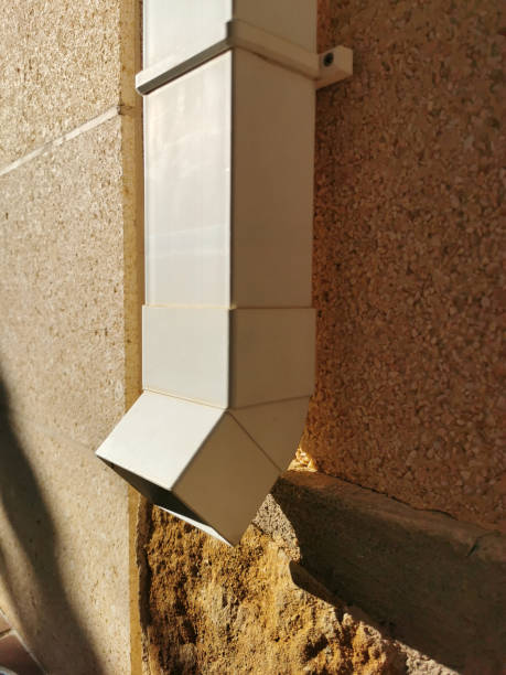 white plastic drain pipe on the brown brick wall. Downspout