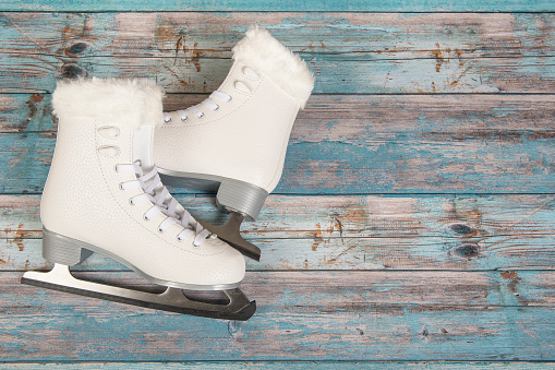 White ice skated for women on a blue wooden background