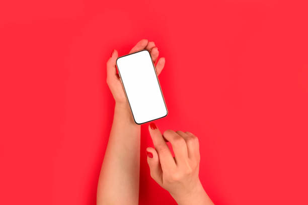 istock Mockup image of woman's hand holding mobile phone with white blank screen on bright red background - online shopping or online education concept. Selective focus 1271275196