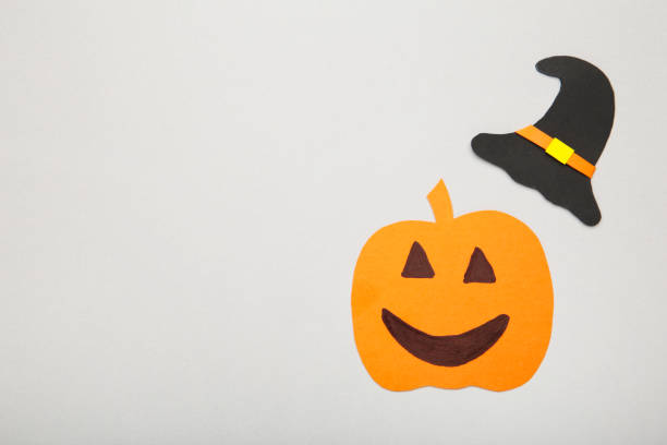 istock Witch hat with pumpkin on grey background. Halloween paper decorations on grey background with copy space. 1271275204