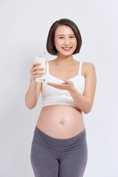 istock pregnant girl drinks milk on a white background 1271275565