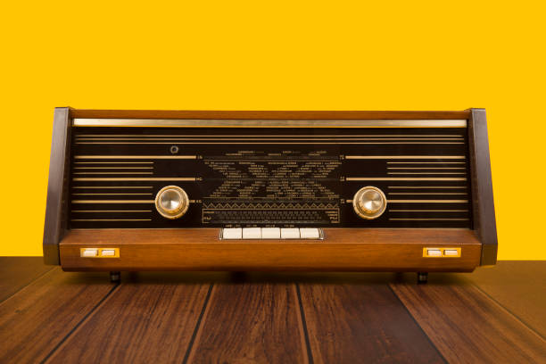 radio antigua antigua sobre un fondo amarillo con mesa de madera marrón oscuro - radio old fashioned antique yellow fotografías e imágenes de stock