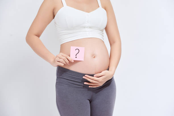 istock Pregnant woman with a sticky note, which is drawing a question sign, on her belly 1271275743