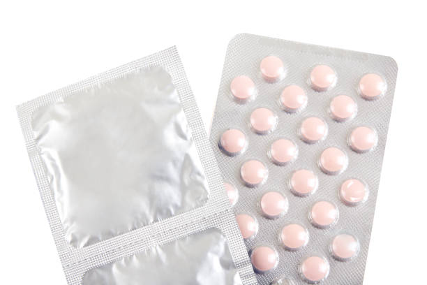 pilules contraceptives et préservatifs sur blanc - contraceptive sex education birth control pill condom photos et images de collection