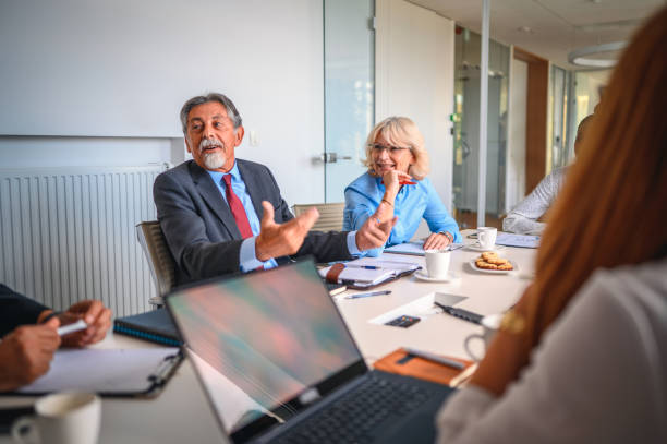 istock Senior Male Executive Talking with Colleagues in Board Room 1271281148