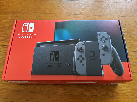 Honolulu - August 26, 2019: Brand New second version model of Nintendo Switch game machine in box on hardwood floor..