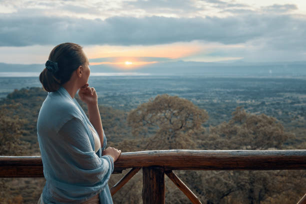 istock Woman alone on terrace watching sunset over mountains during summer vacation 1271282975