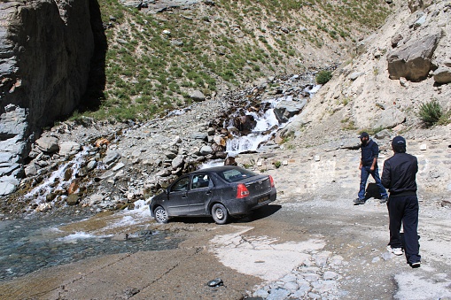 Keylong, Himachal Pradesh, India - August 17, 2012 : A car crossing a small rivulet passing along the road towards keylong in Himachal Pradesh, India. Kyelang (or Keylong) is the administrative centre of the Lahaul and Spiti district in the Indian state of Himachal Pradesh, 126 km (78 mi) north of Manali and 120 km (75 mi) from the Indo-Tibetan border. It is located along the Manali-Leh Highway, about 7 km (4.3 mi) north-east of intersection of the Chandra Valley, the Bhaga Valley, and the Chenab Valley; on the banks of Bhaga River.