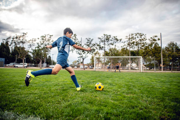 portrait d’action du footballeur de garçon approchant le ballon pour le coup de pied - fitness goal photos et images de collection