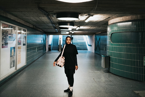 young muslim sports woman with hijab standing in subway station in Berlin and looking to camera