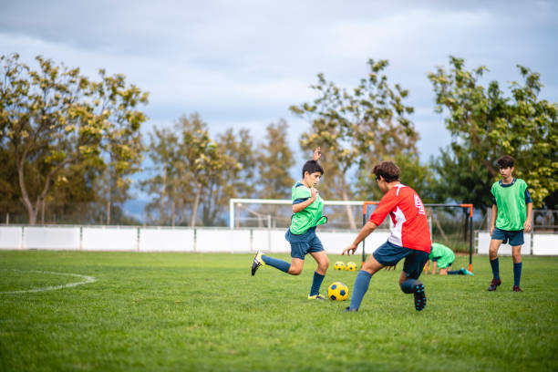 Teenage Male Footballers Dribbling and Defending in Practice Boy athletes aged 12-16 playing practice match during sports training camp. youth sports competition stock pictures, royalty-free photos & images