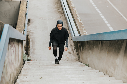 high angle view on young muslim sports woman with sports hijab running up concrete stairs in Berlin
