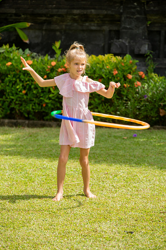 Young happy girl having fun with hula hoop outside in the park