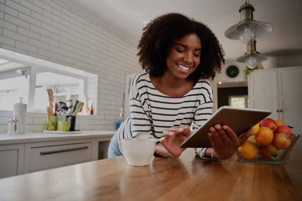 istock African American Woman standing in kitchen leaning on counter using digital tablet looking at online recipes 1271286398