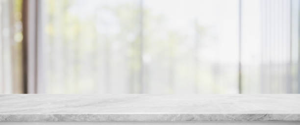 istock Empty white marble stone table top and blurred living room in home interior with curtain window banner background. - can used for display or montage your products. 1271286483