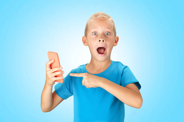 Funny surprised boy holding smartphone. Over blue background