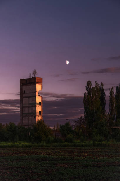 istock Abandoned tower at purple evening sky and moon background 1271288145