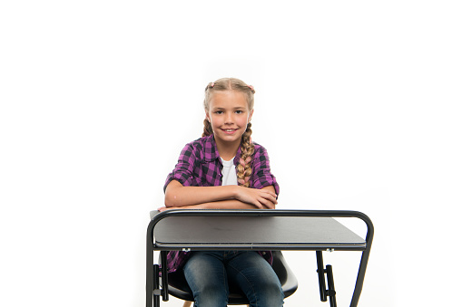 Back to school. Cute school child sitting at desk isolated on white. Little schoolgirl having lesson in primary school. Adorable small girl enjoying her school time.
