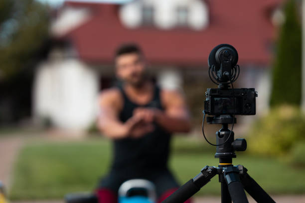 istock Male athlete sitting on exercise mat and making vlog at backyard. 1271295246