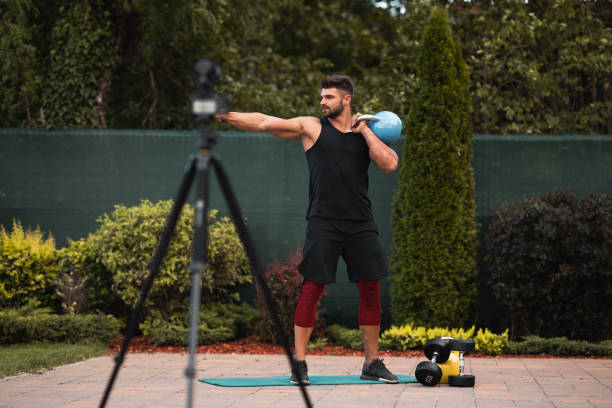 istock Male athlete doing exercise in backyard and filming vlog. 1271295315
